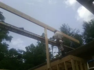 Carpenter setting a ridge beam over a new addition frame — Ice Dam Removal by Roofing Brothers in North Falmouth