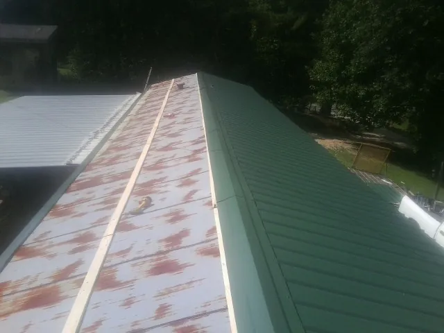 Old rusted panels beside newly installed green metal roofing — Wind Damage Roof Repair by Roofing Brothers in North Falmouth