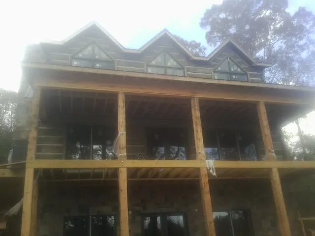 Dormers and porch framing on a large log home under construction — Roof Coating work by our crew in North Falmouth