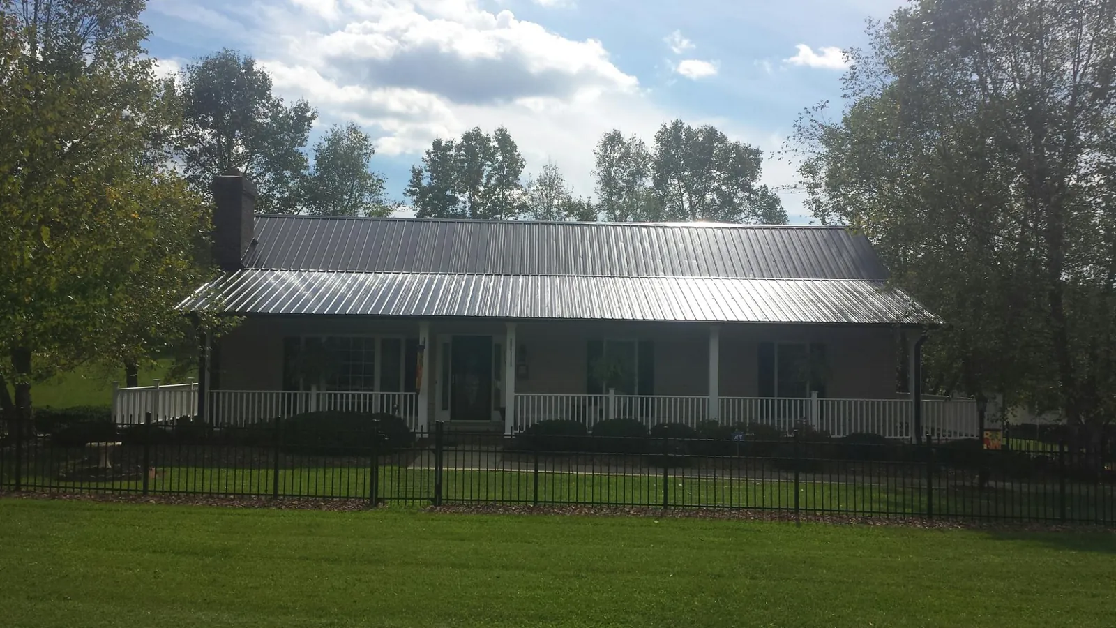 Gray metal roof on a brick ranch with a full width front porch — Gutter Guard Installation work by our crew in North Falmouth