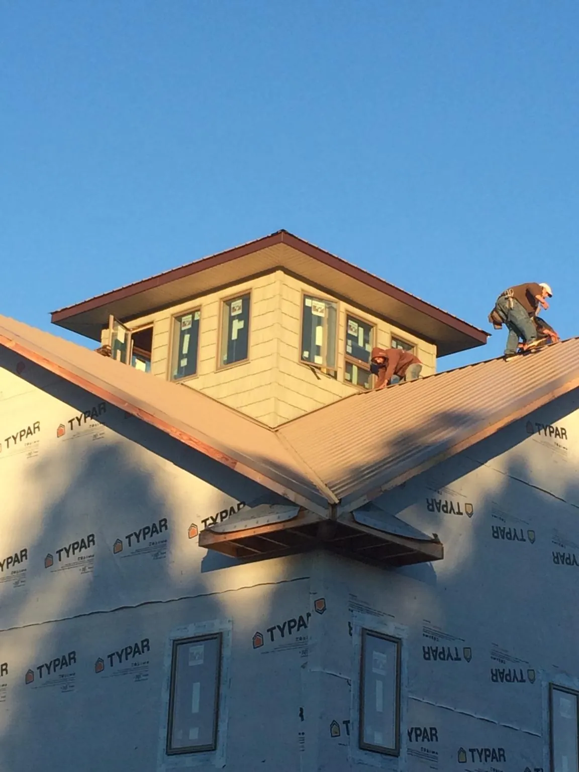 Roofers working around a rooftop cupola on a new metal roof at sunset — Roof Waterproofing in North Falmouth by Roofing Brothers